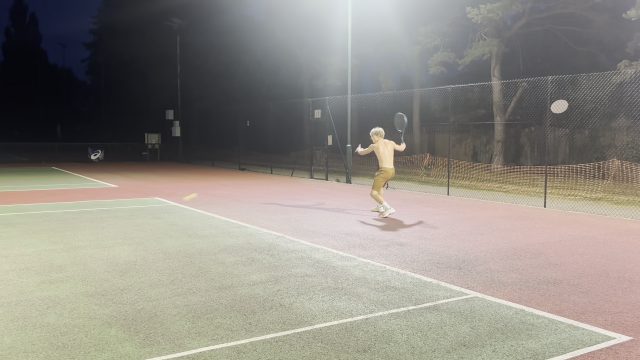 A night court filmed from far away. The player is a small figure in the distance.